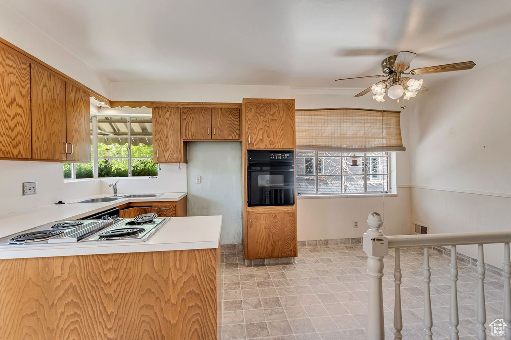 Kitchen with ceiling fan, oven, sink, light tile flooring, and stainless steel gas cooktop