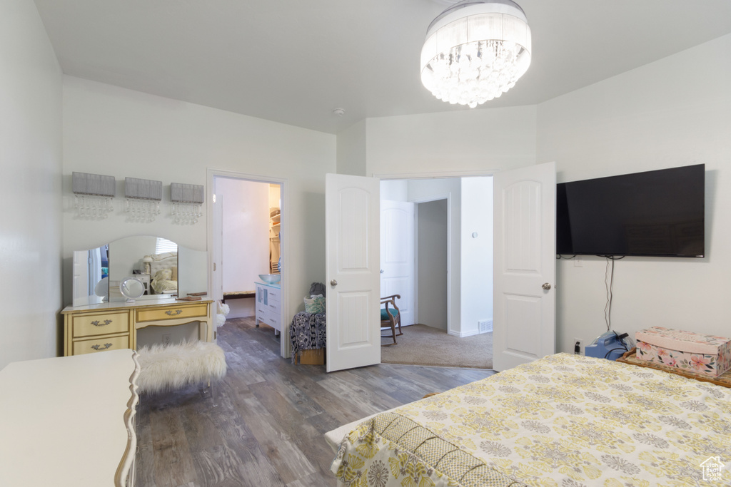 Bedroom featuring dark hardwood / wood-style floors, ensuite bathroom, and an inviting chandelier
