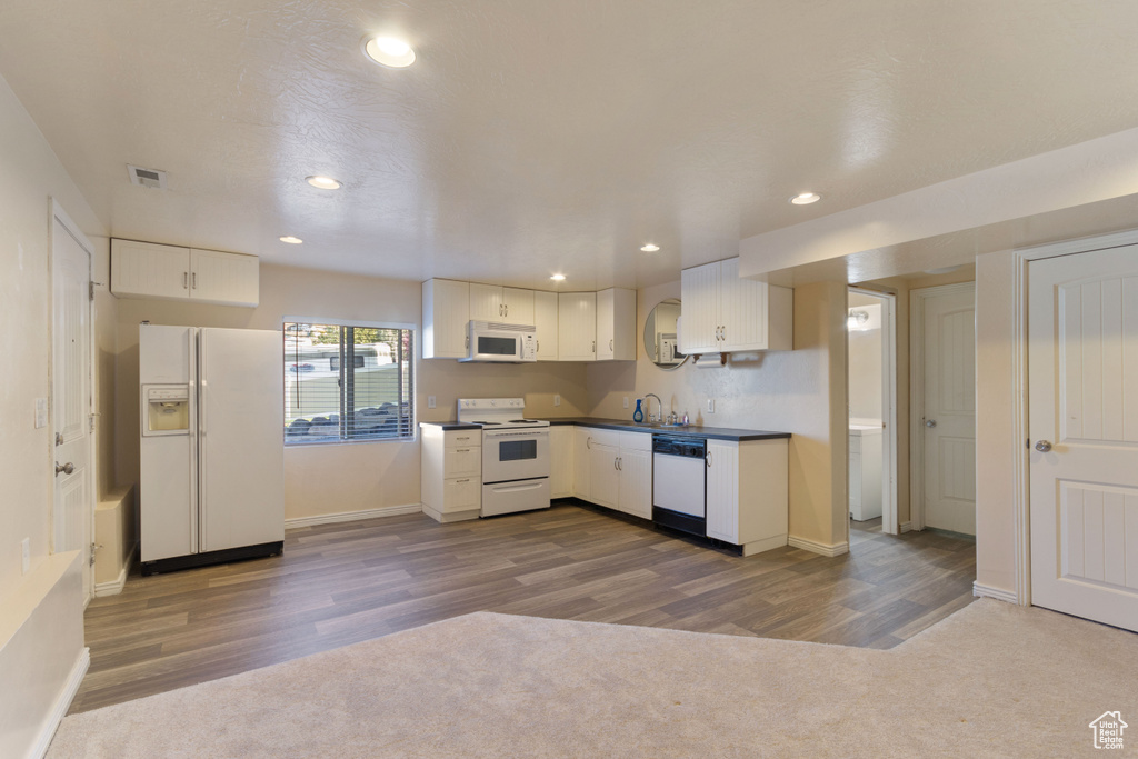 Kitchen featuring white appliances, sink, and carpet flooring