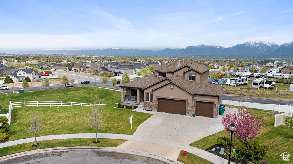 View of front of property with a garage, a mountain view, and a front lawn