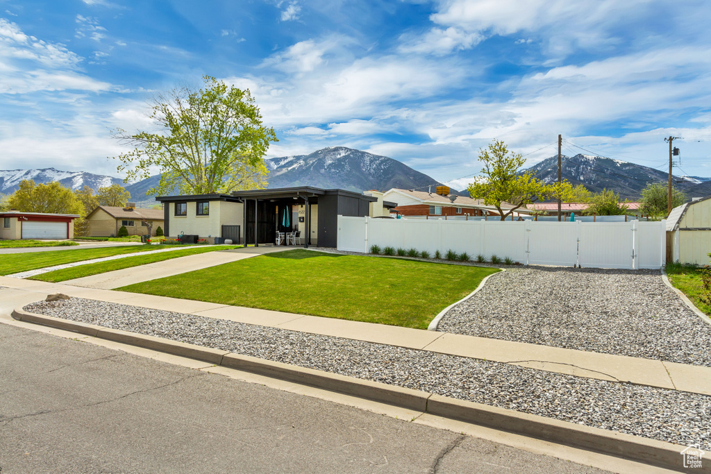View of front of home featuring a mountain view, a garage, and a front lawn