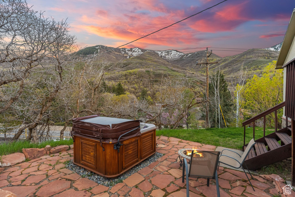 Patio terrace at dusk with a mountain view and a hot tub