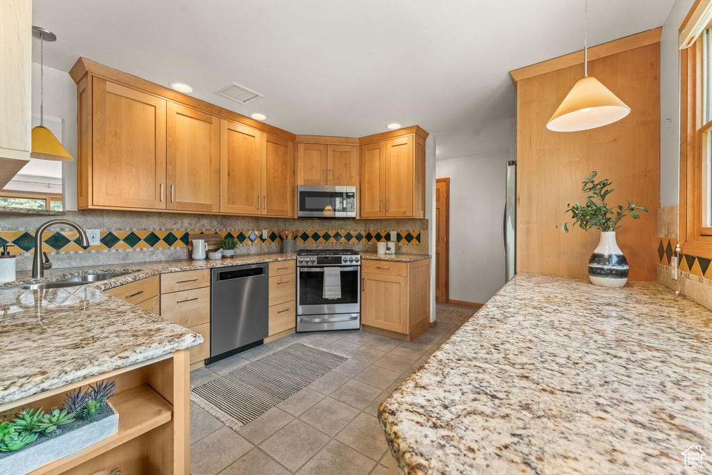 Kitchen with backsplash, pendant lighting, stainless steel appliances, and light tile floors
