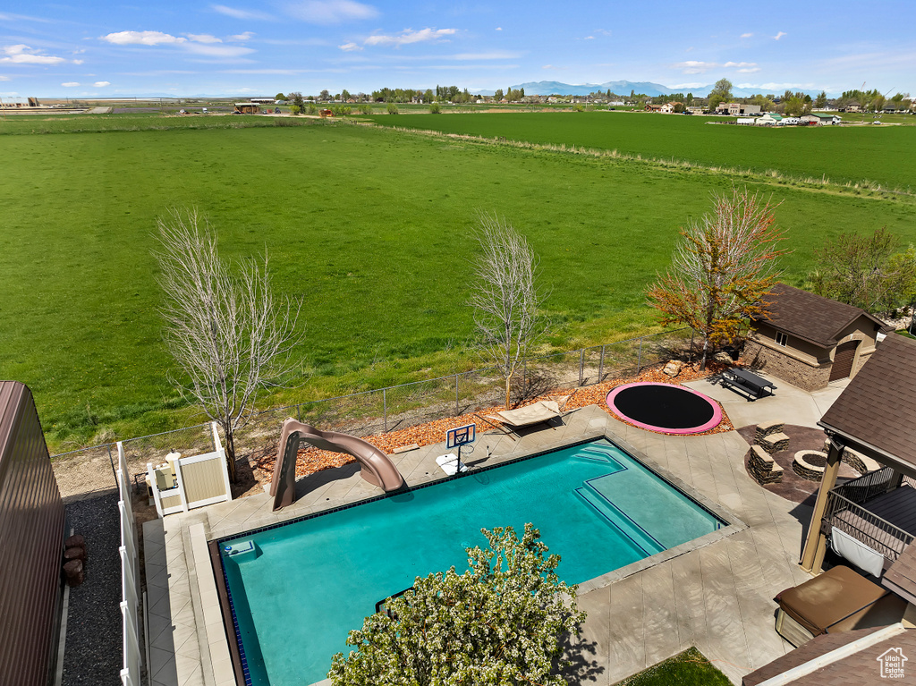 View of pool with a patio and a rural view