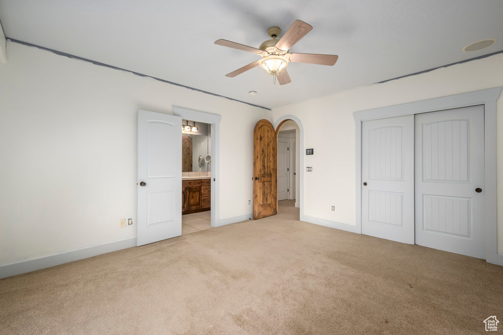 Unfurnished bedroom with light colored carpet, a closet, ceiling fan, and connected bathroom