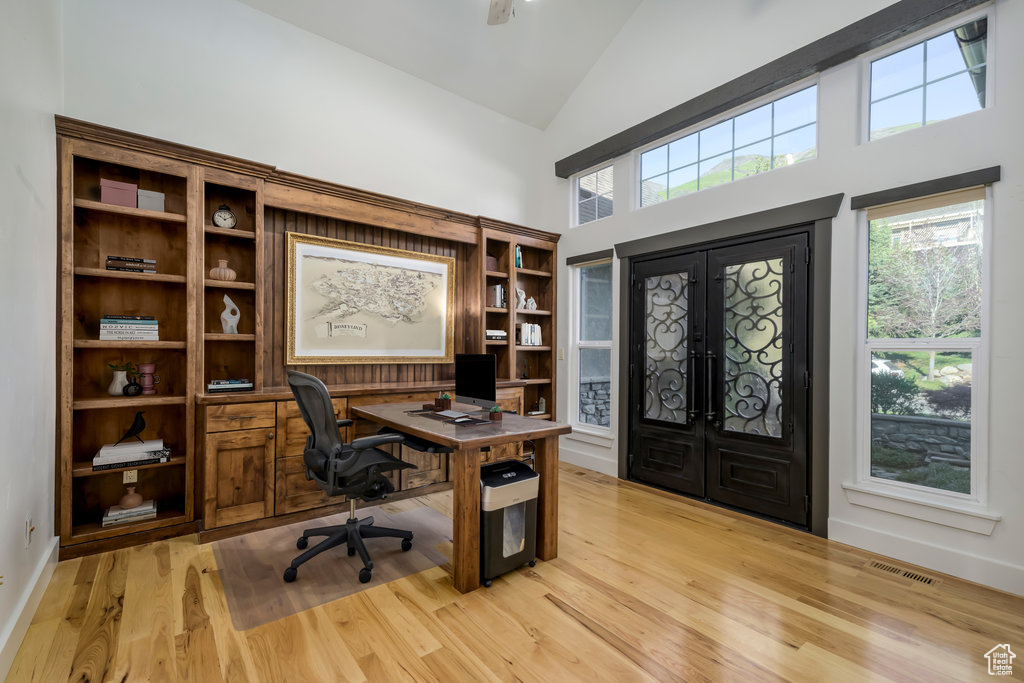 Office with high vaulted ceiling, light hardwood / wood-style flooring, and french doors