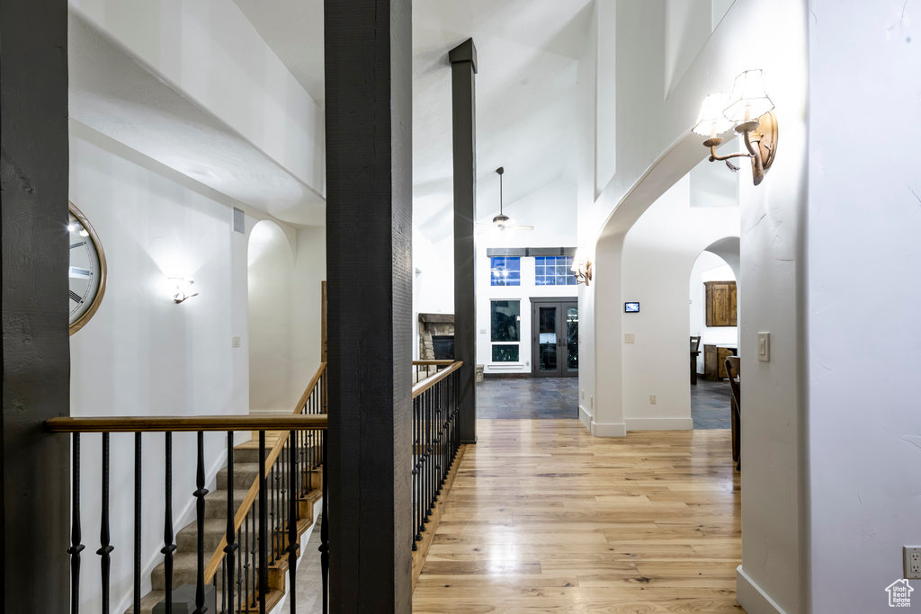 Hall with high vaulted ceiling and light hardwood / wood-style floors