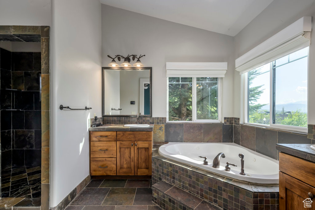Bathroom featuring tile flooring, vaulted ceiling, vanity, and a healthy amount of sunlight