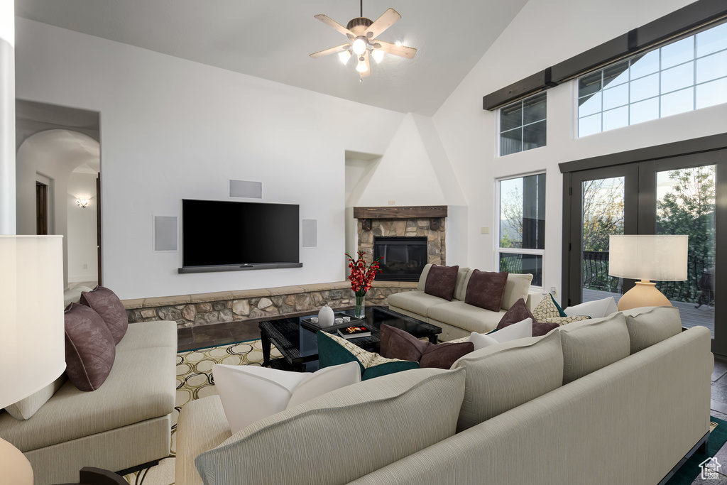 Living room with a stone fireplace, high vaulted ceiling, wood-type flooring, and ceiling fan