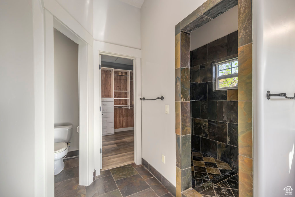 Bathroom with tiled shower, tile floors, and toilet