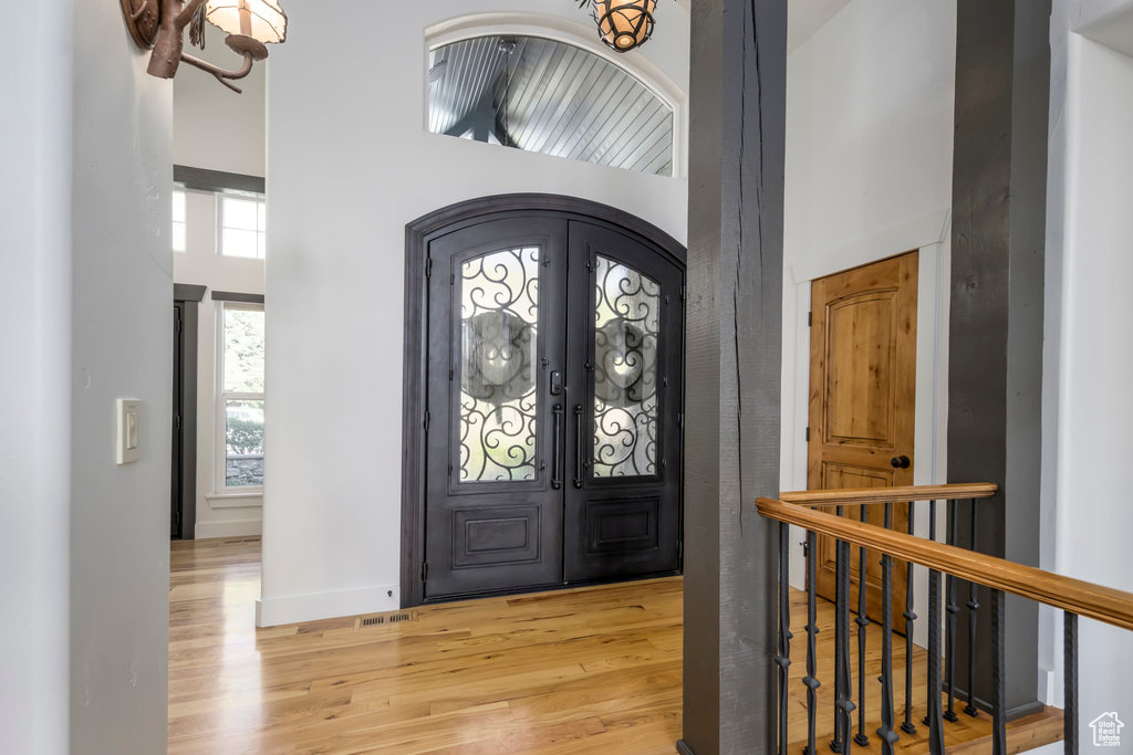 Foyer with french doors, a towering ceiling, and light wood-type flooring