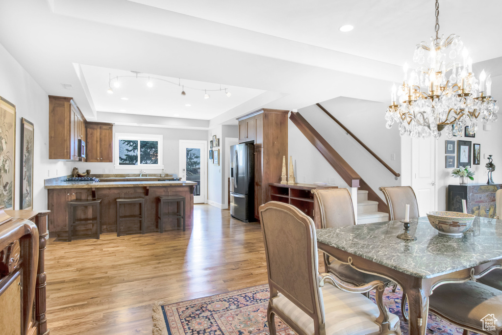 Dining area featuring sink, hardwood / wood-style floors, a tray ceiling, and an inviting chandelier