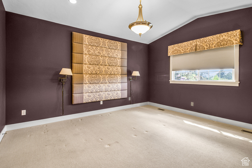 Unfurnished room featuring carpet and vaulted ceiling