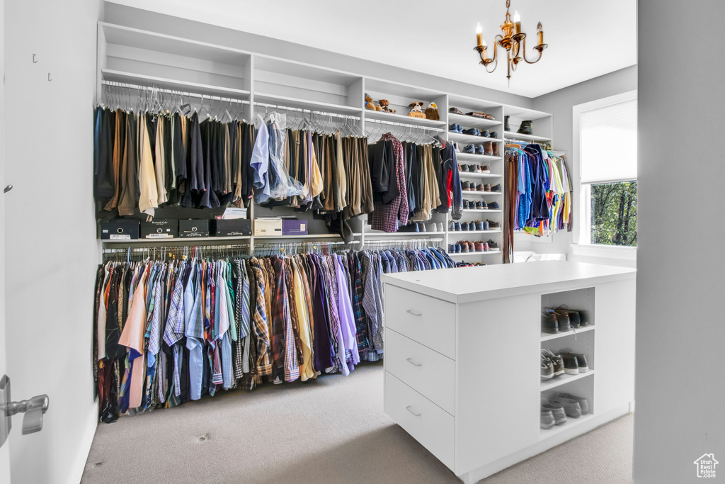 Walk in closet with light carpet and a chandelier