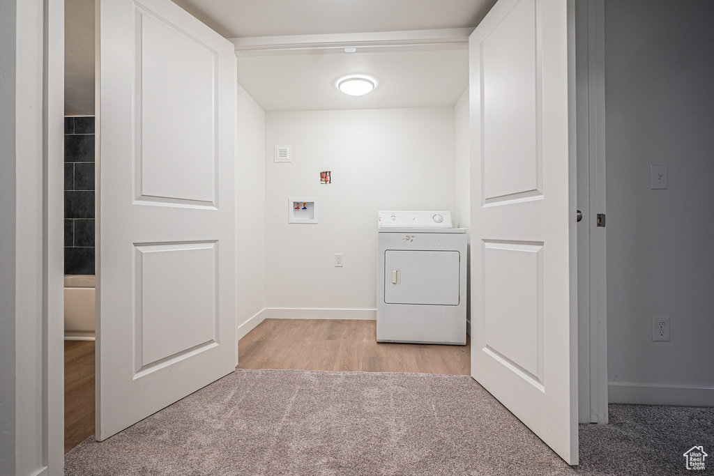 Laundry room featuring light colored carpet and washer / dryer