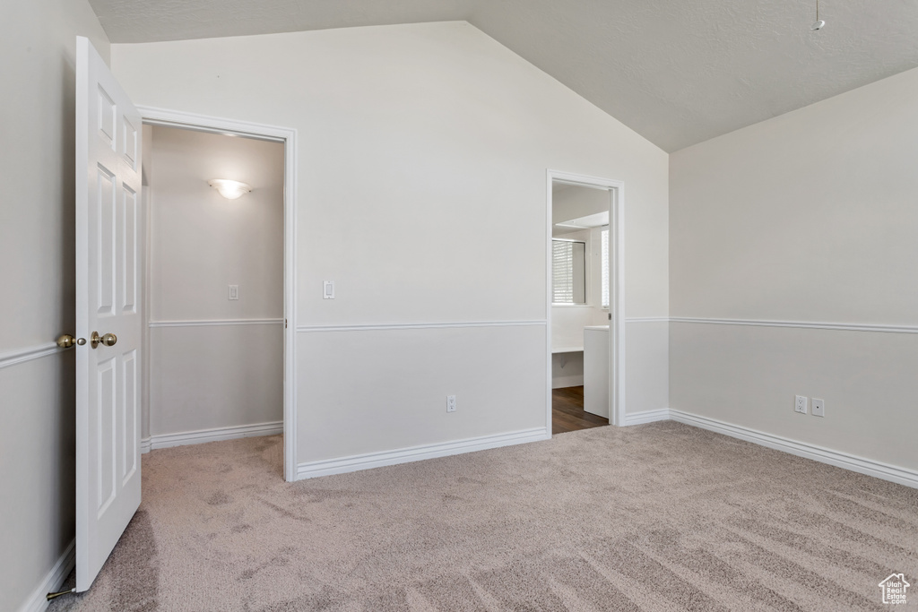 Unfurnished bedroom featuring carpet floors and lofted ceiling