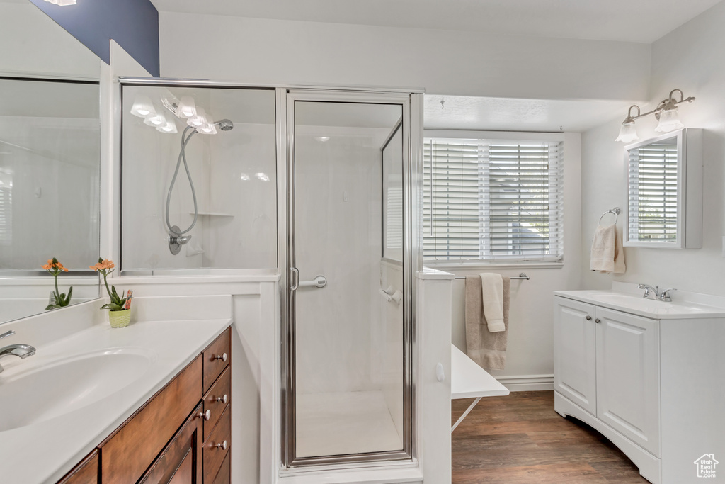 Bathroom featuring hardwood / wood-style flooring, double sink, oversized vanity, and walk in shower