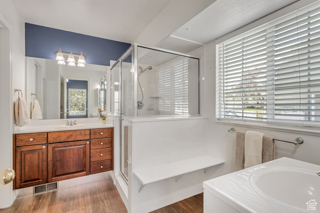 Bathroom with oversized vanity, hardwood / wood-style floors, and shower with separate bathtub
