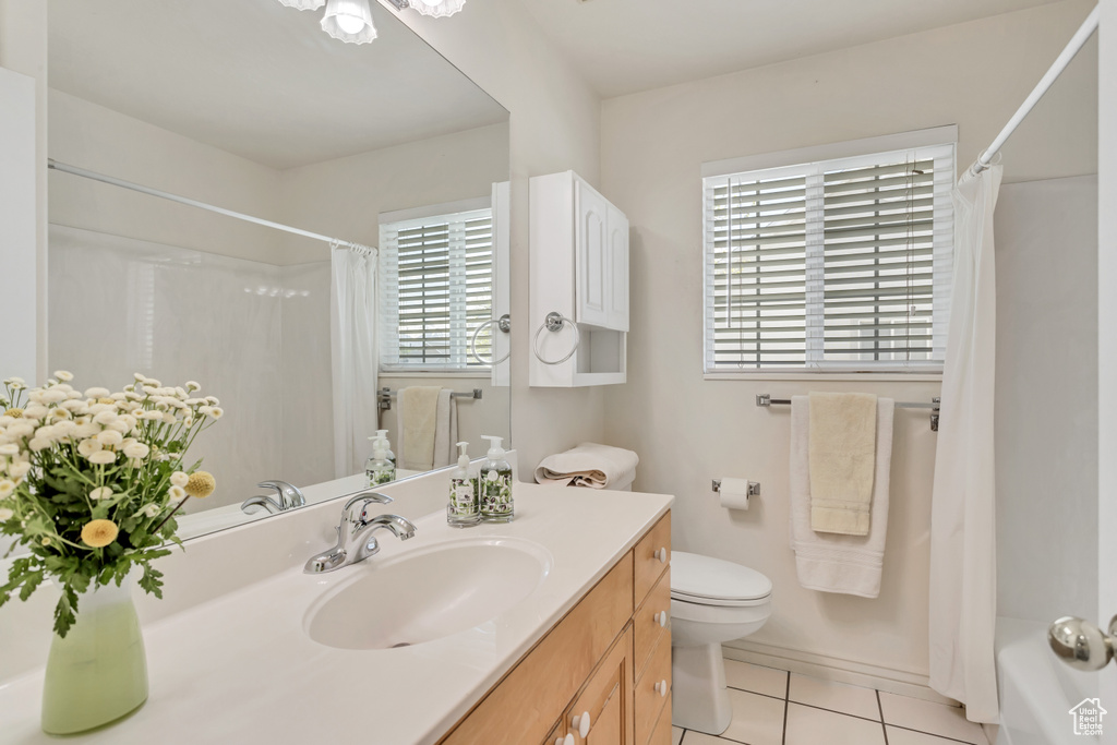 Full bathroom featuring vanity with extensive cabinet space, toilet, tile floors, and shower / bath combination with curtain