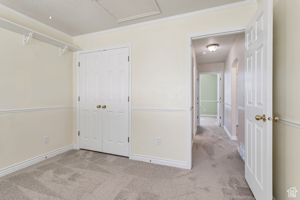 Unfurnished bedroom featuring a closet, carpet flooring, and crown molding