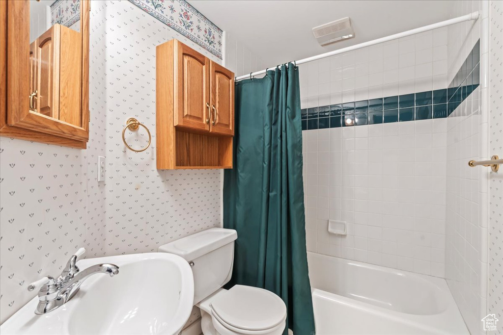 Full bathroom with sink, shower / bath combination with curtain, and toilet