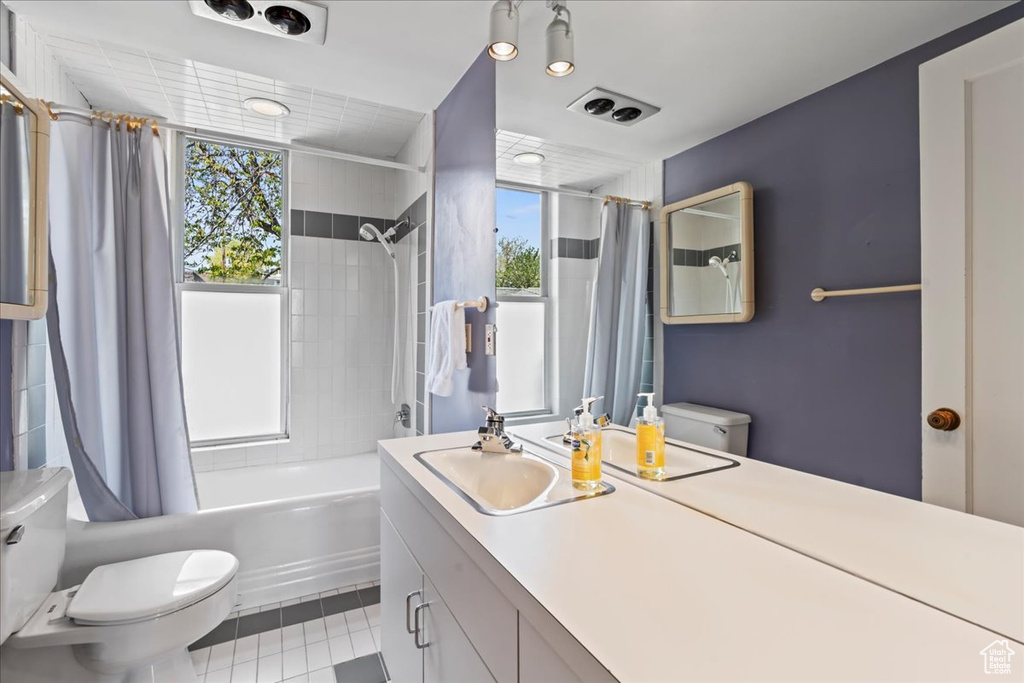 Full bathroom featuring plenty of natural light, shower / bath combo, toilet, and tile flooring