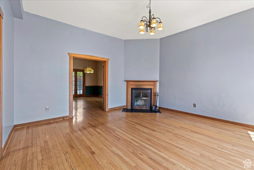 Unfurnished living room with light hardwood / wood-style flooring and a notable chandelier