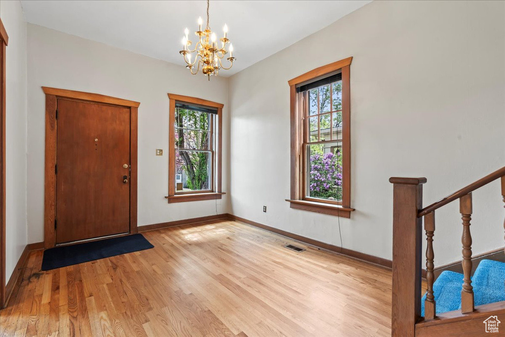 Entryway with plenty of natural light, a notable chandelier, and light wood-type flooring