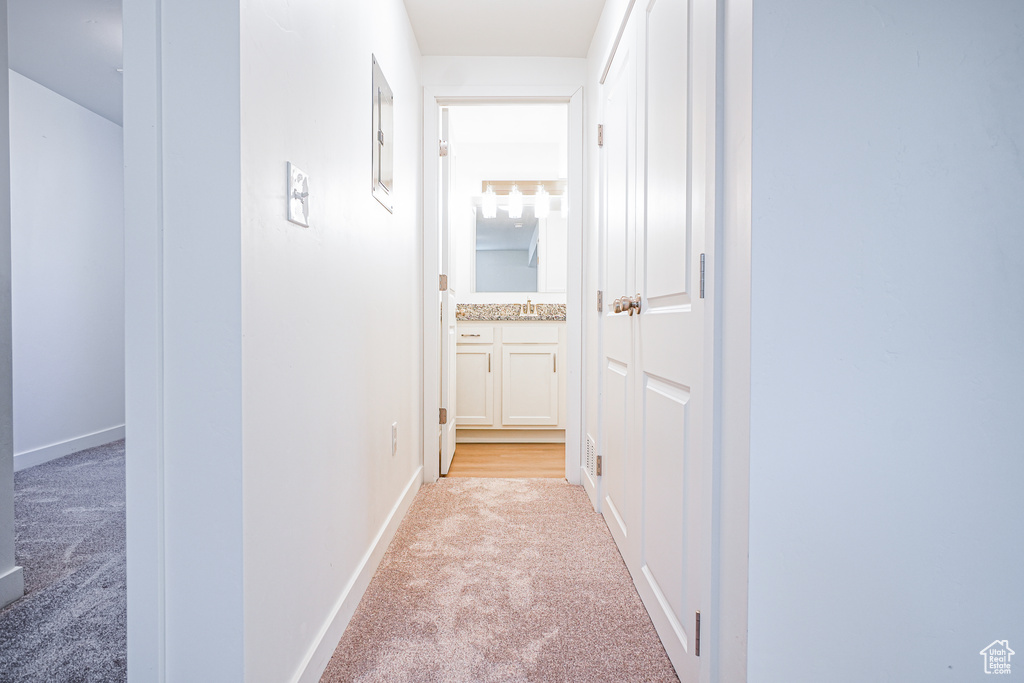 Corridor featuring light colored carpet and sink