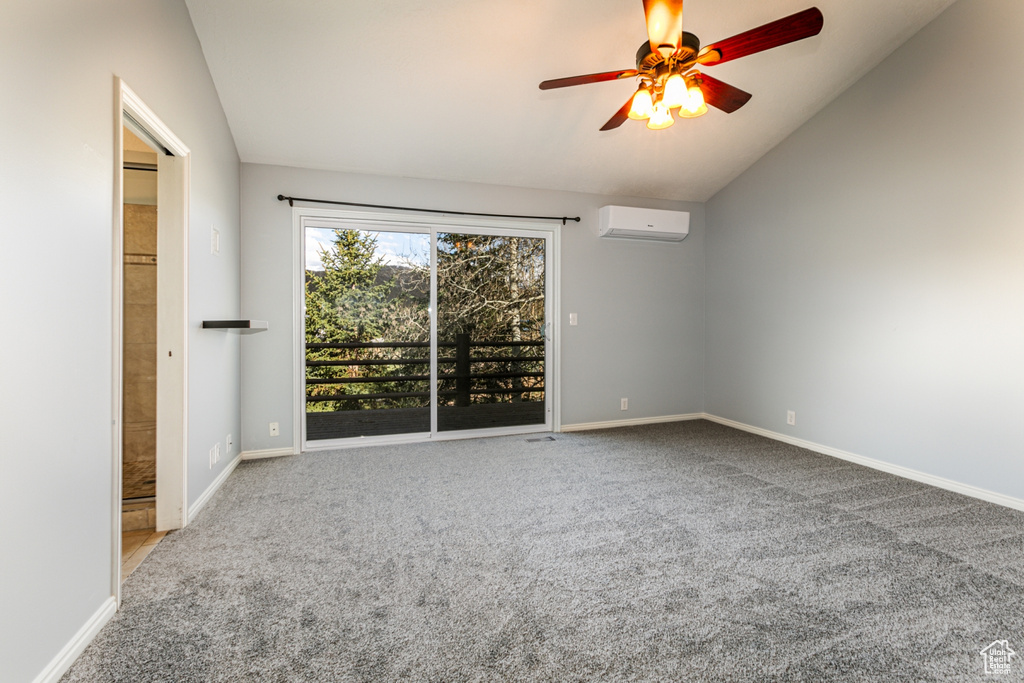 Carpeted empty room with lofted ceiling, a wall mounted AC, and ceiling fan