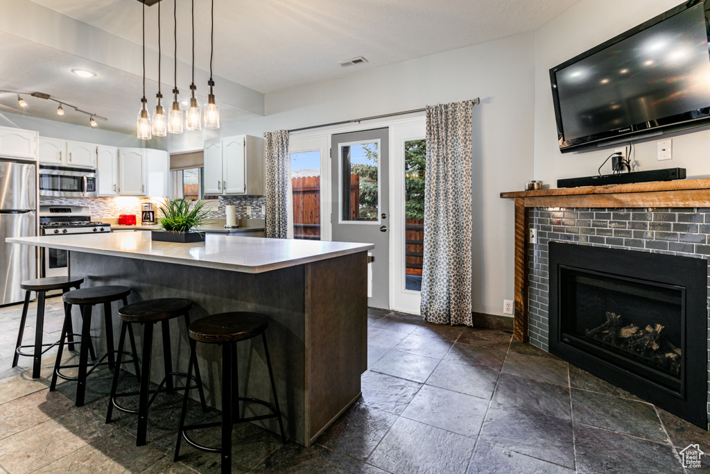 Kitchen featuring backsplash, dark tile floors, stainless steel appliances, and white cabinets
