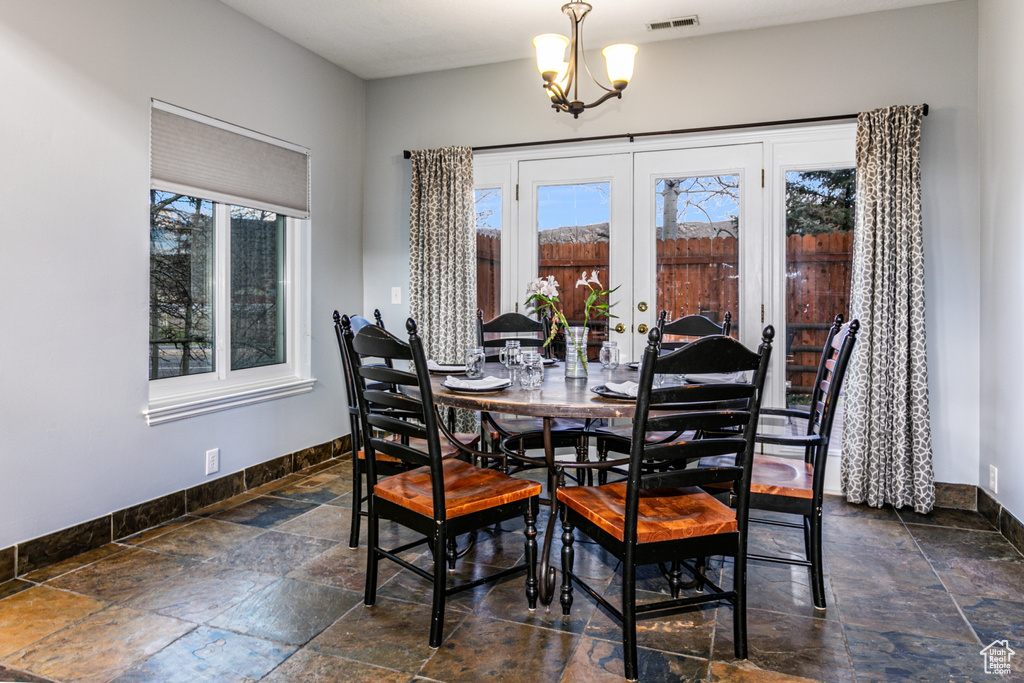 Dining room featuring dark tile flooring, french doors, and a chandelier