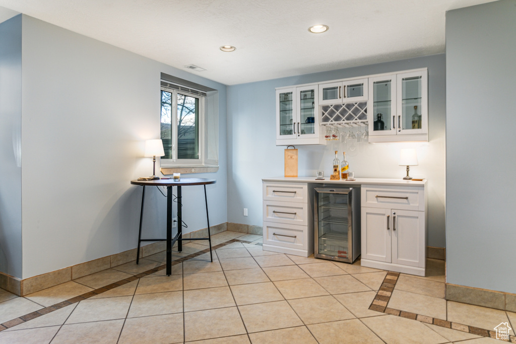 Bar featuring beverage cooler, light tile flooring, and white cabinets