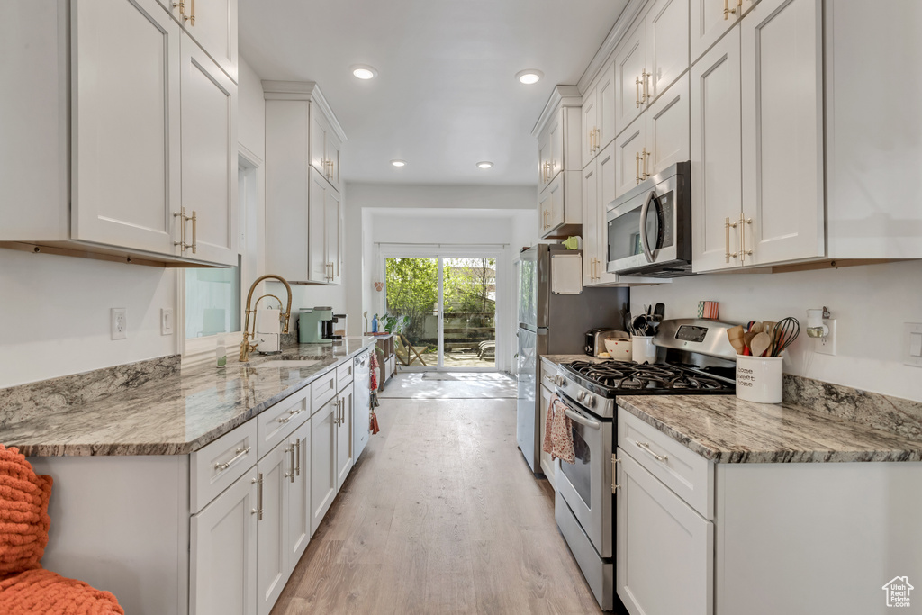 Kitchen featuring white cabinets, sink, light hardwood / wood-style flooring, and stainless steel appliances