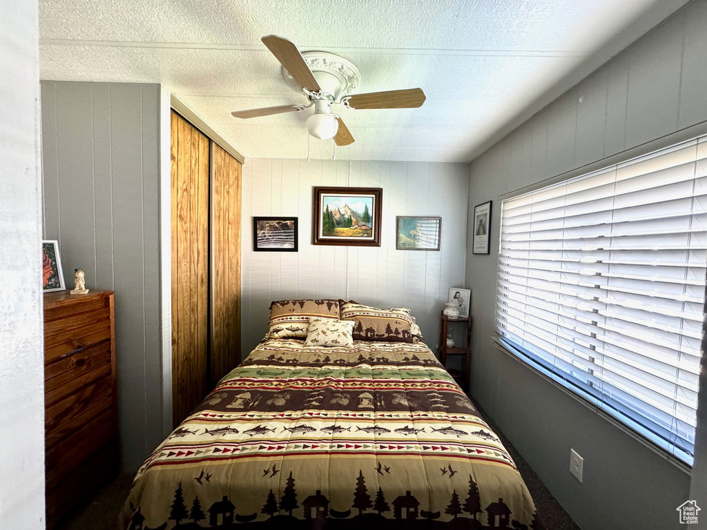Bedroom with a closet, ceiling fan, and a textured ceiling