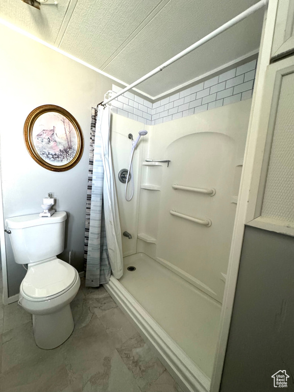 Bathroom featuring tile flooring, toilet, and a shower with shower curtain