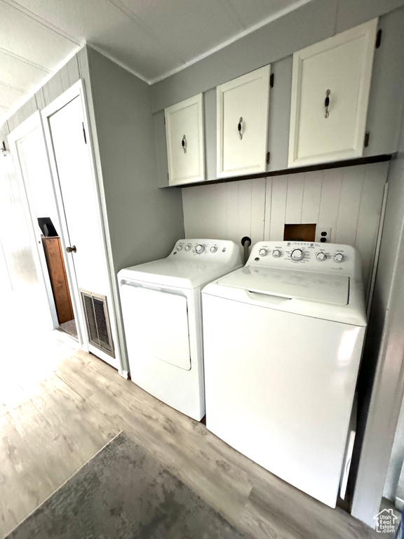 Laundry room featuring light hardwood / wood-style flooring, independent washer and dryer, and cabinets