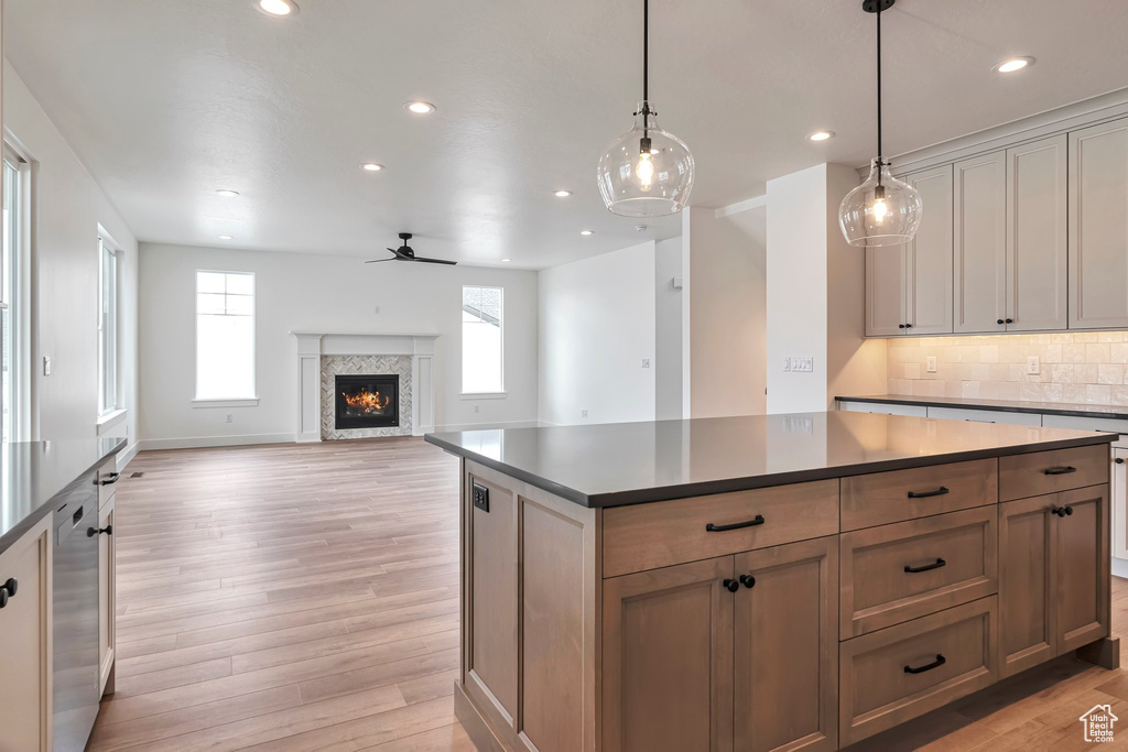 Kitchen with a kitchen island, tasteful backsplash, ceiling fan, and light wood-type flooring