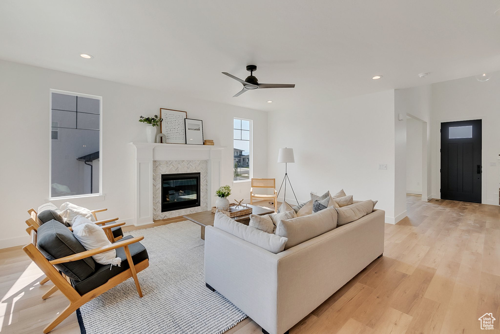 Living room with a fireplace, ceiling fan, and light hardwood / wood-style floors