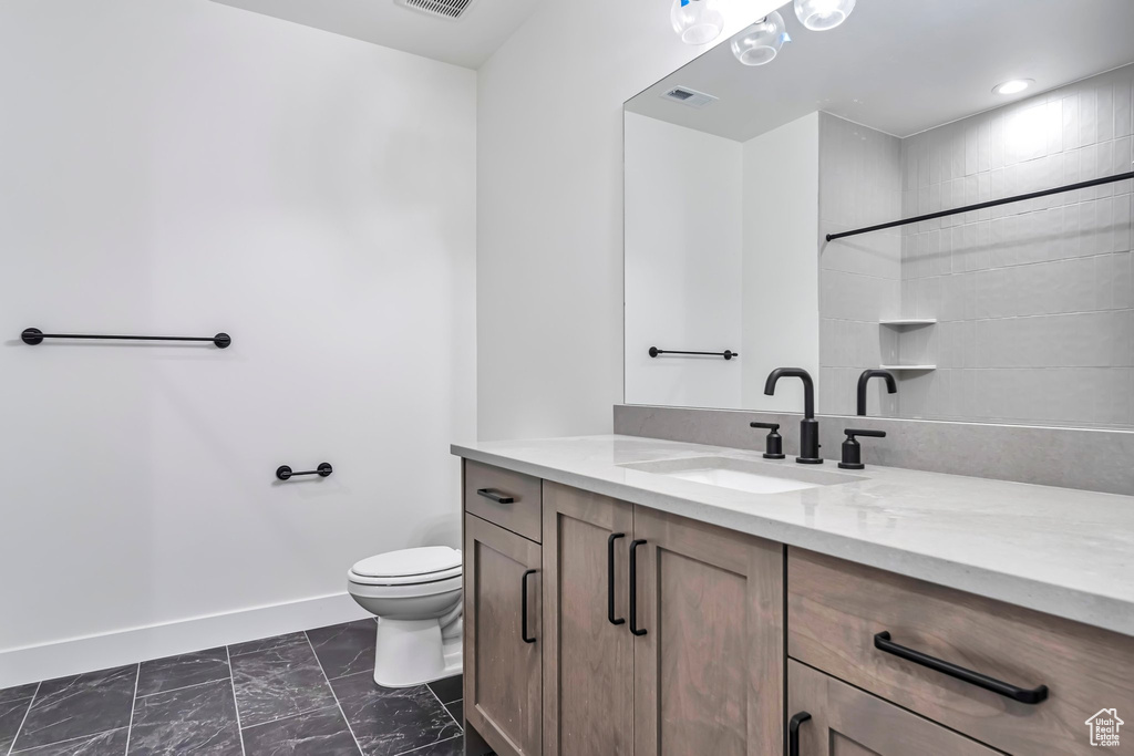 Bathroom featuring vanity with extensive cabinet space, toilet, and tile floors