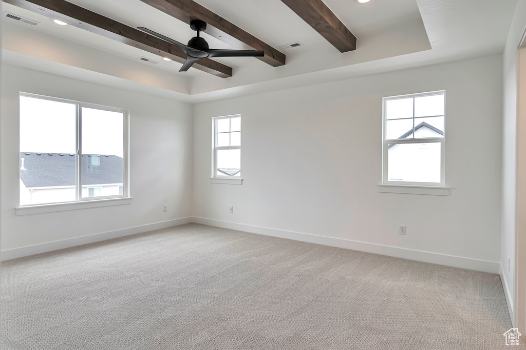 Unfurnished room with light carpet, beamed ceiling, ceiling fan, and a tray ceiling