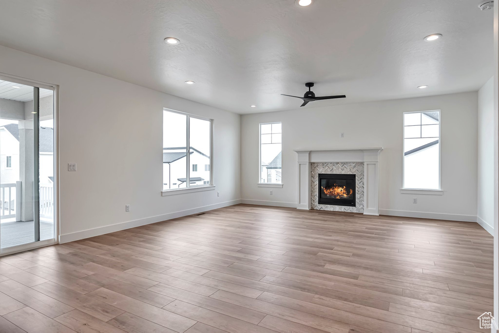 Unfurnished living room with ceiling fan, light wood-type flooring, and a fireplace