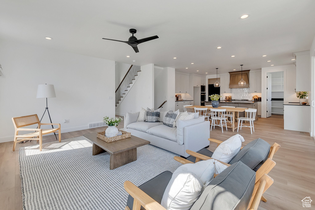 Living room with light hardwood / wood-style floors and ceiling fan