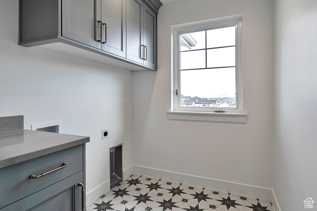 Washroom with a healthy amount of sunlight, hookup for an electric dryer, cabinets, and light tile floors