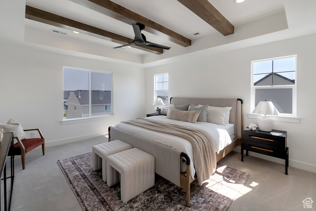 Carpeted bedroom featuring beam ceiling and ceiling fan