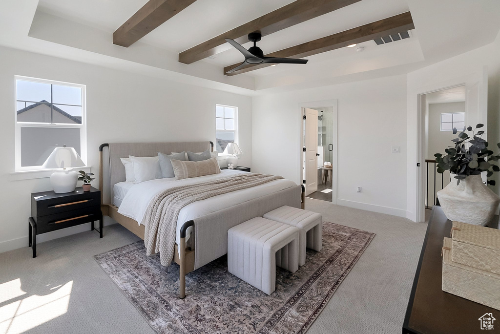 Carpeted bedroom with beamed ceiling, connected bathroom, a raised ceiling, and ceiling fan