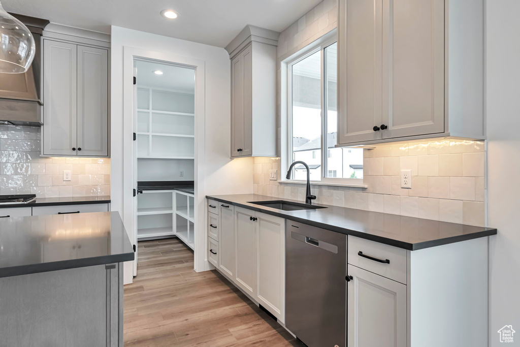 Kitchen with stainless steel dishwasher, sink, tasteful backsplash, and light wood-type flooring