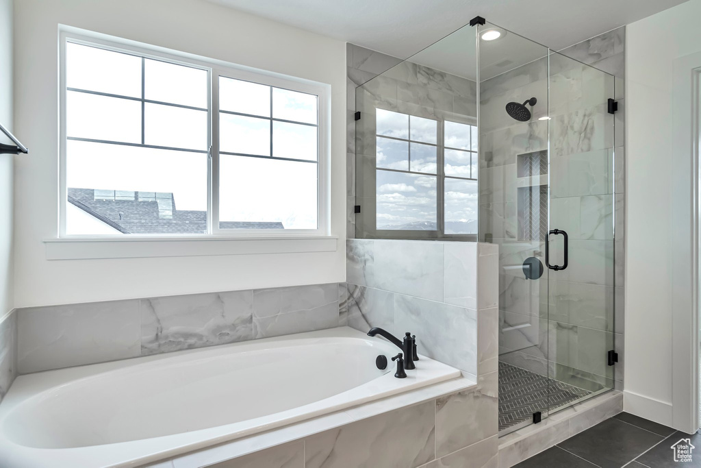 Bathroom featuring plus walk in shower, a wealth of natural light, and tile flooring