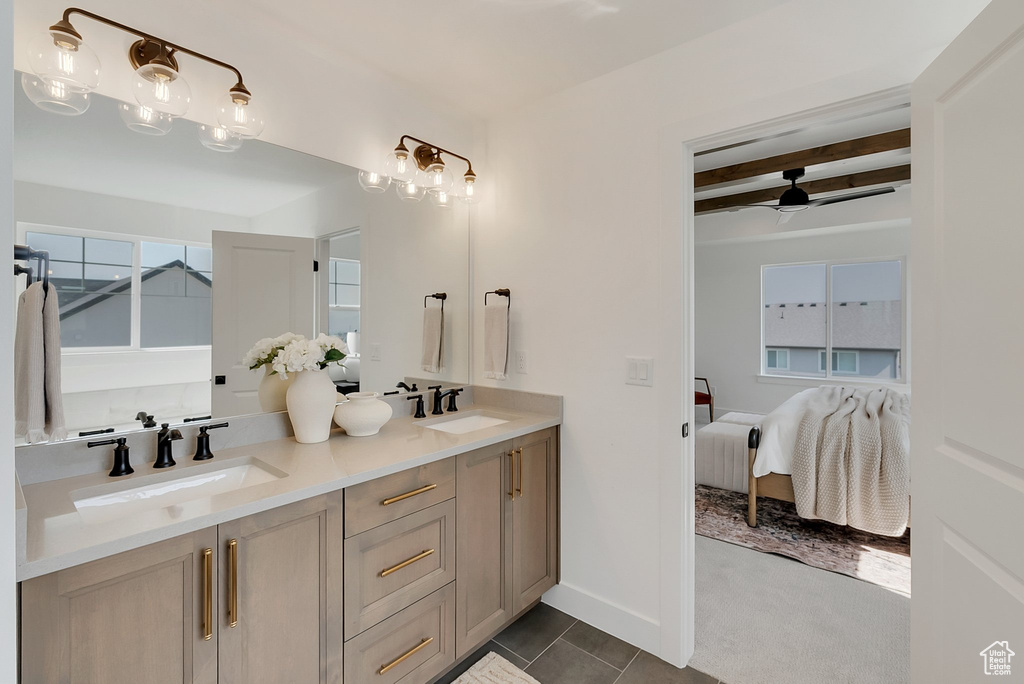 Bathroom with beamed ceiling, tile patterned floors, ceiling fan, and dual bowl vanity