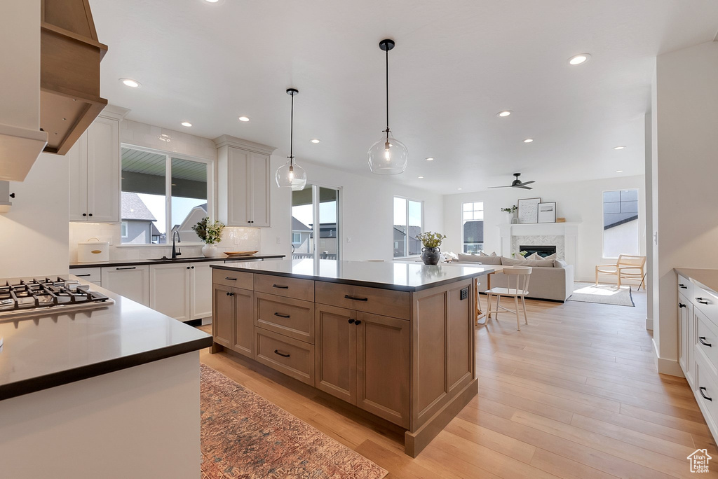 Kitchen featuring a kitchen island, white cabinetry, light wood-type flooring, and a wealth of natural light